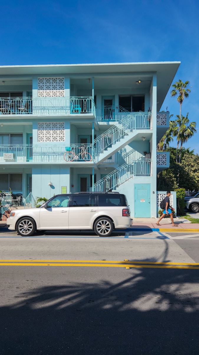 A white car parked in front of a blue building
